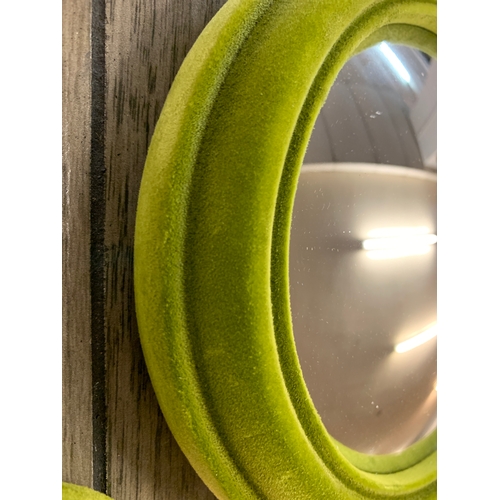 1385 - A set of seven green velvet framed graduated convex mirrors