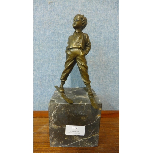 358 - A bronze figure of a young boy on skis, on grey marble socle