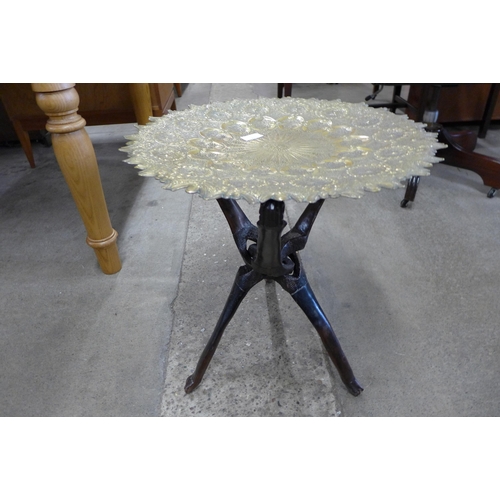 117 - An Indian brass topped occasional table, on naturalistic wooden folding stand