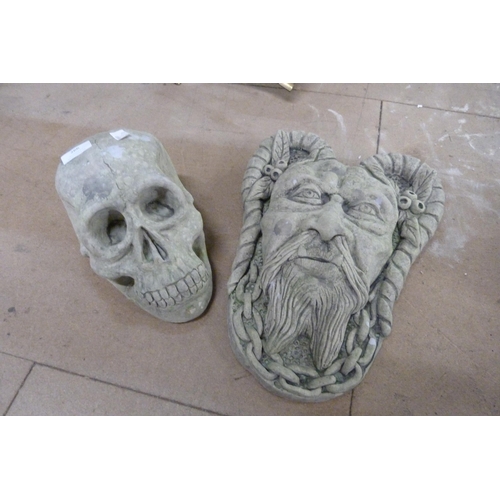 266 - A concrete garden wall hanging face mask and a skull