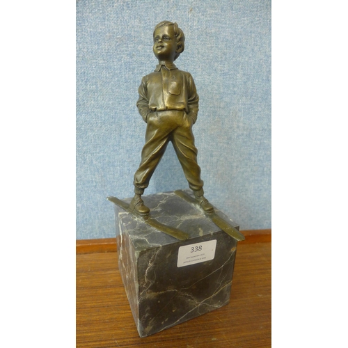 338 - A bronze figure of a young boy on skis, on grey marble socle