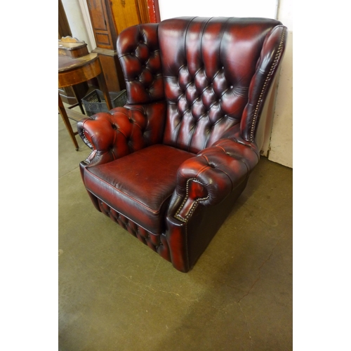 93 - An oxblood red leather Chesterfield wingback armchair