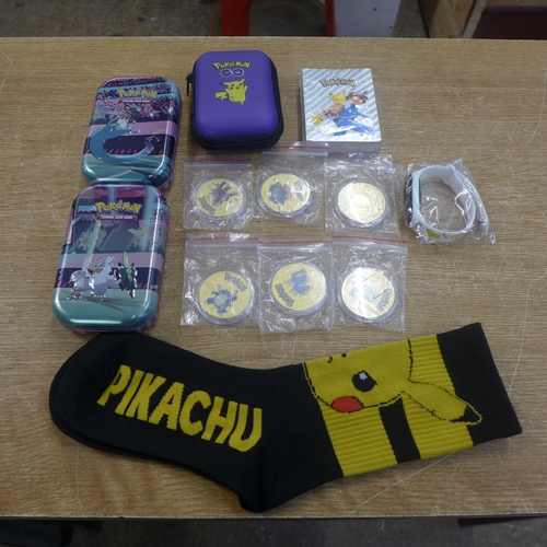 2147 - A selection of Pokemon collector items including:- 6 gold coloured coins, pair of socks, watch, card... 