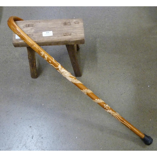 830 - A wooden stool and walking stick with dragon motif