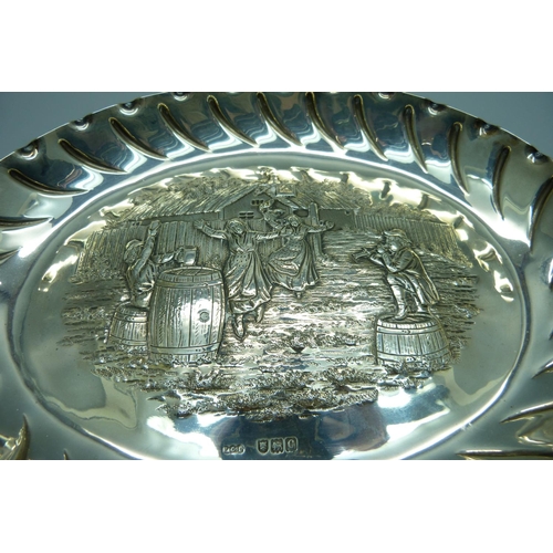 852 - An oval silver tray with embossed scene of an outside tavern, ladies dancing to a piper with seated ... 