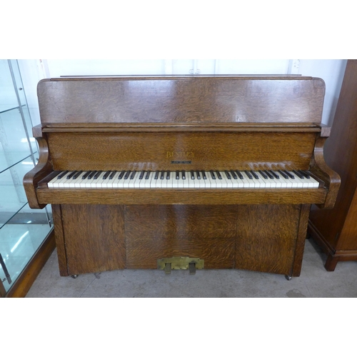 116 - An Art Deco Bentley oak overstrung upright piano, with faux ivory plastic keys, retailed by Ascotts,... 