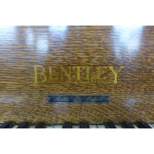 116 - An Art Deco Bentley oak overstrung upright piano, with faux ivory plastic keys, retailed by Ascotts,... 