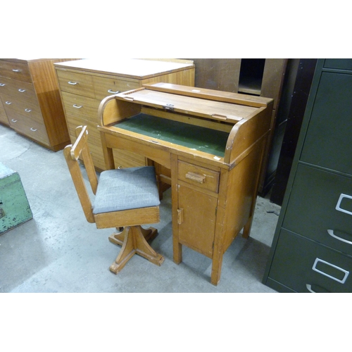 228 - An early 20th Century child's beech roll top desk and revolving chair