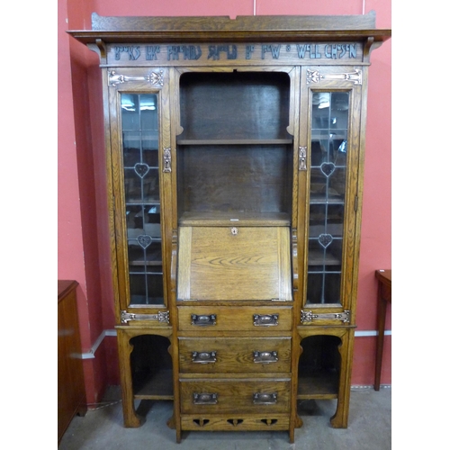 87 - An Arts and Crafts Liberty & Co. oak bureau bookcase, with inscription; Books Like Friends Should Be... 