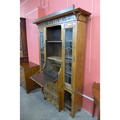 87 - An Arts and Crafts Liberty & Co. oak bureau bookcase, with inscription; Books Like Friends Should Be... 