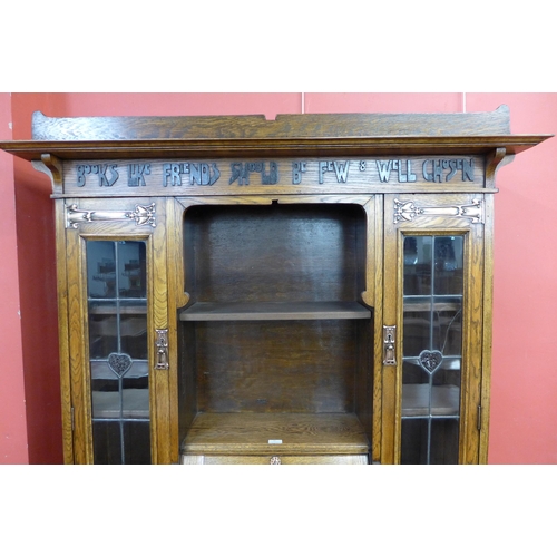 87 - An Arts and Crafts Liberty & Co. oak bureau bookcase, with inscription; Books Like Friends Should Be... 