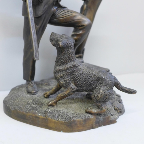 692 - A cast metal sculpture of a gamekeeper and his dog