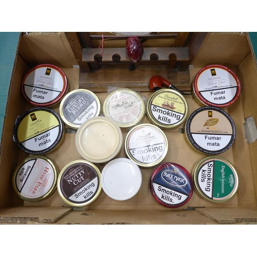 727 - A collection of fourteen tins of pipe tobacco, a rack and two pipes