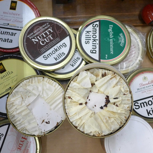 727 - A collection of fourteen tins of pipe tobacco, a rack and two pipes