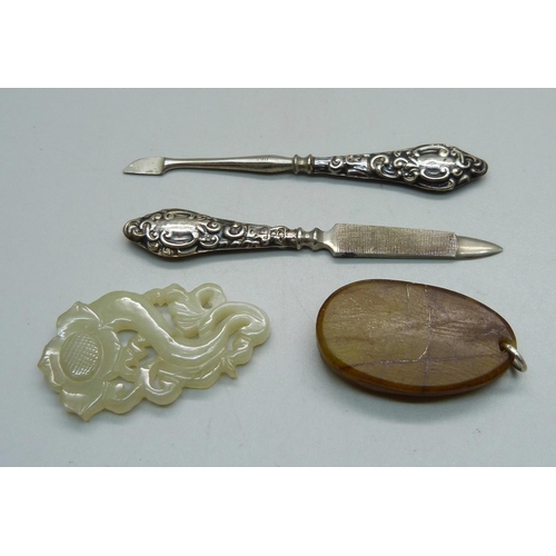 861A - A carved jade pendant, one other pendant and two silver mounted manicure tools