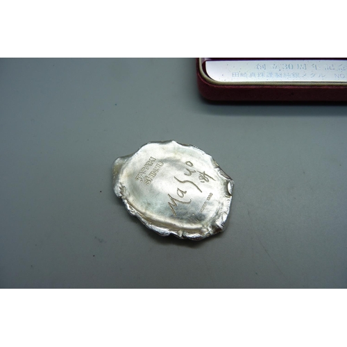 886 - A Japanese '1000 Silver' cast of a face, Woman in the Hat, stamped Tasaki Shinju and signed Masuo '8... 