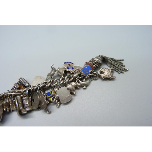 948 - A heavy silver charm bracelet with approximately 55 silver and white metal charms including drilled ... 