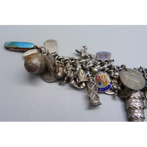 948 - A heavy silver charm bracelet with approximately 55 silver and white metal charms including drilled ... 