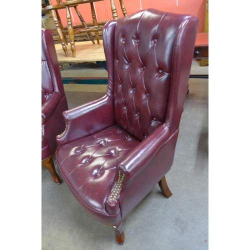 113 - A pair of Queen Anne style faux burgundy leather wingback armchairs