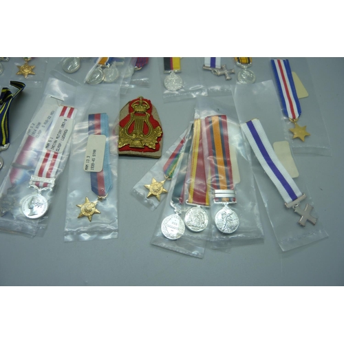 876 - Five WWII medals, a collection of replica miniature medals, a military cap, a badge and a pocket wat... 