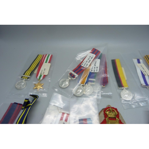 876 - Five WWII medals, a collection of replica miniature medals, a military cap, a badge and a pocket wat... 