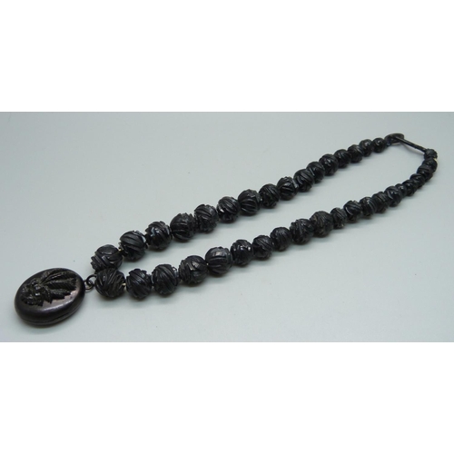 934 - A Victorian carved jet bead necklace with locket