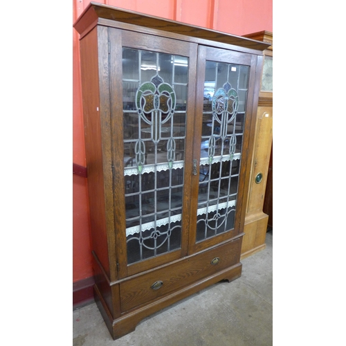 105 - An Arts and Crafts oak and stained glass two door bookcase