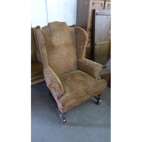 235 - A 1920's Queen Anne style mahogany and fabric upholstered wingback armchair