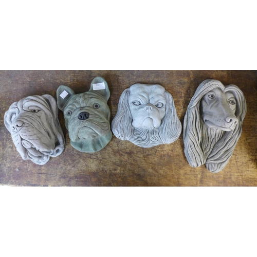 358 - Four assorted concrete wall mounted garden dog's heads