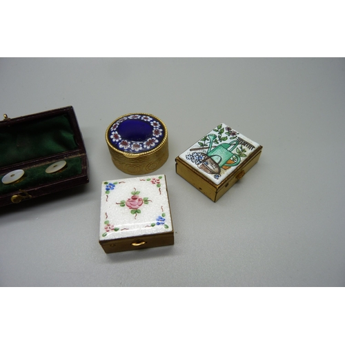 1010 - A guilloche enamel topped pill box, two other enamelled pill boxes and a cased set of mother of pear... 