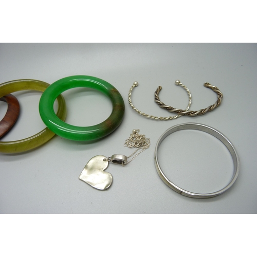 877 - Two jade bangles, a wooden bangle, a white metal mirror, three bangles and a pendant and chain