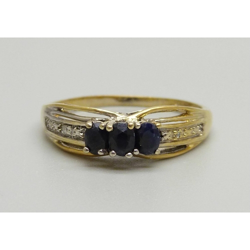 929 - A silver gilt and three sapphire ring with two small diamond accents on the shoulders, X