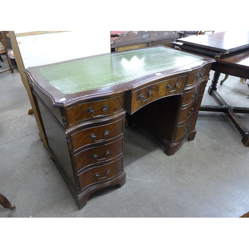 105 - A mahogany and green leather topped serpentine pedestal desk