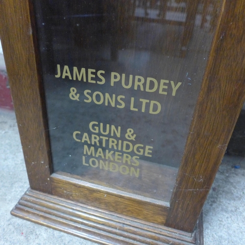 210 - A glazed oak single door cabinet, bearing Purdey Gun & Rifle Makers inscription to door