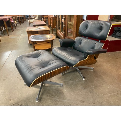 1 - A Charles & Ray Eames style simulated rosewood and black leather revolving lounge chair and ottoman