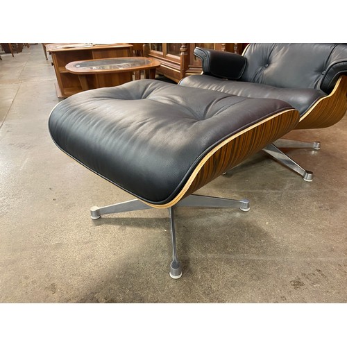 1 - A Charles & Ray Eames style simulated rosewood and black leather revolving lounge chair and ottoman