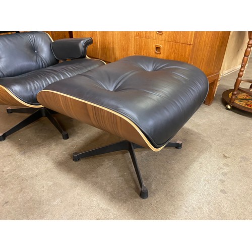 4 - A Charles & Ray Eames style simulated rosewood and black leather revolving lounge chair and ottoman