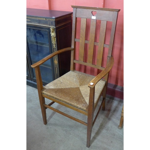 74 - An Arts and Crafts Liberty & Co. style oak and rush seated fireside chair, manner of C.F.A. Voysey