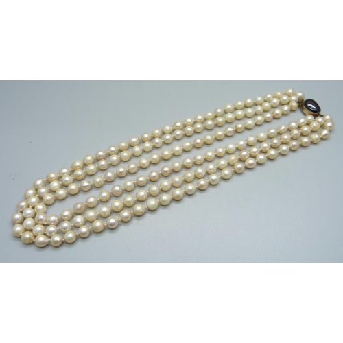 1029 - A triple row of baroque pearls on a Victorian yellow metal and cabochon garnet clasp, 94.7g, 44cm, (... 