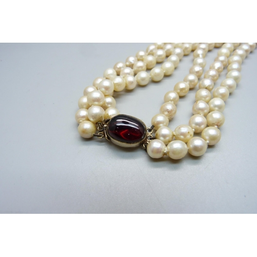 1029 - A triple row of baroque pearls on a Victorian yellow metal and cabochon garnet clasp, 94.7g, 44cm, (... 