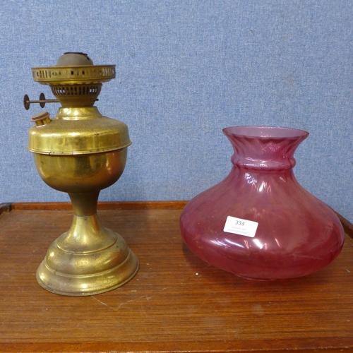 333 - A brass oil lamp, with cranberry glass shade