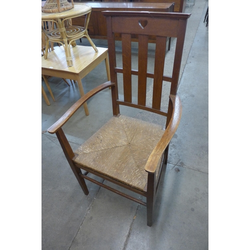 65 - An Arts and Crafts Liberty & Co. style oak and rush seated fireside chair, manner of C.F.A. Voysey