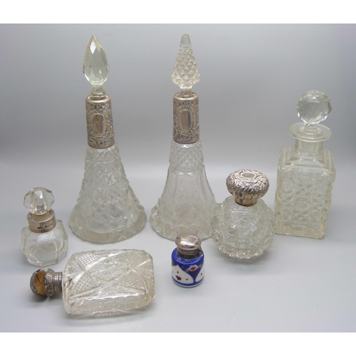 868 - A collection of five cut glass scent bottles with silver tops/collars, a small porcelain silver topp... 