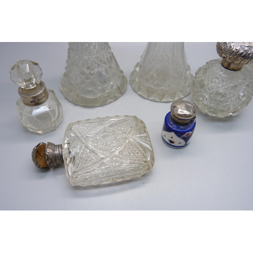 868 - A collection of five cut glass scent bottles with silver tops/collars, a small porcelain silver topp... 