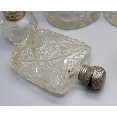 868 - A collection of five cut glass scent bottles with silver tops/collars, a small porcelain silver topp... 