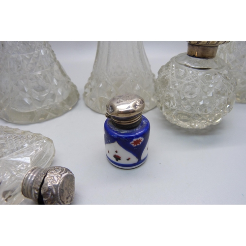 868 - A collection of five cut glass scent bottles with silver tops/collars, a small porcelain silver topp... 