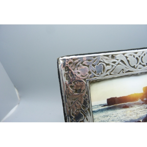 919 - A silver photograph frame, London 1985, 12cm x 16cm, and a hand mirror with engraved detail, Eastern... 