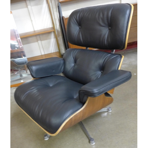 27 - A Charles & Ray Eames style simulated rosewood and black leather revolving lounge chair and ottoman