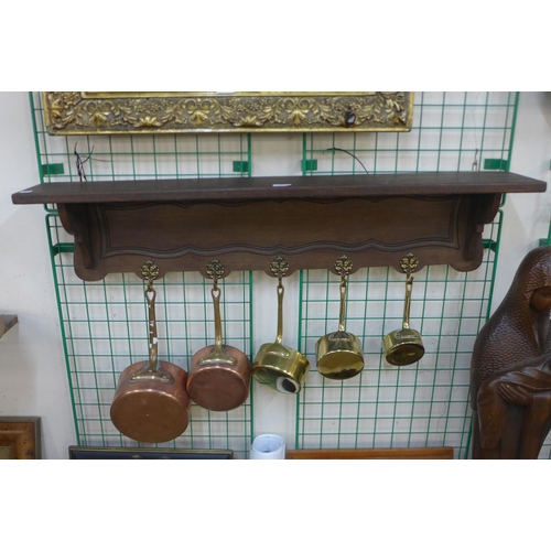 386 - A French oak wall hanging saucepan rack, with copper and brass pans