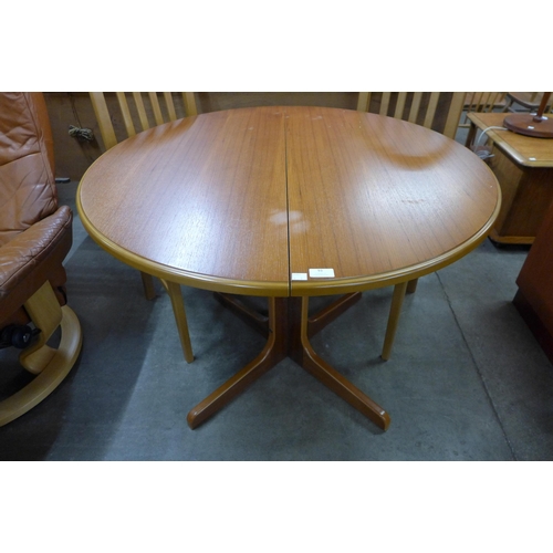 93 - A teak circular extending dining table and four Sakol teak dining chairs